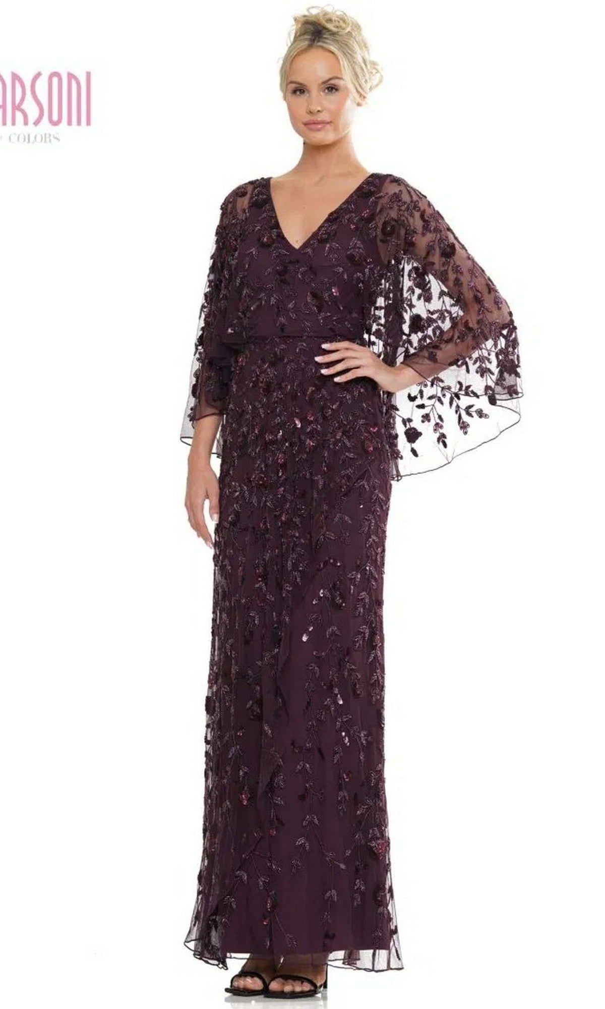 A woman stands facing forward in the Marsoni MV1282 long formal dress—an eggplant floor-length gown with sheer, embroidered sleeves, floral embellishments, and a wrap-style column skirt.